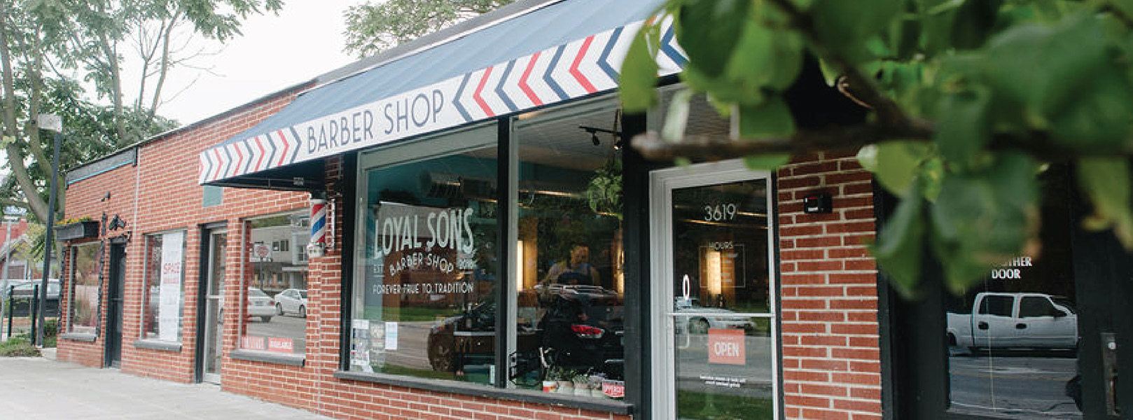 Brick exterior and navy awning of Loyal Sons Barber Shop in Des Moines, Iowa