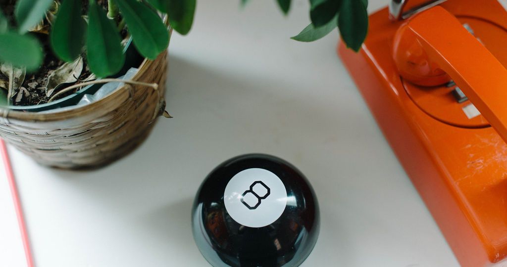 Magic 8 Ball on a white table next to a plant and orange telephone in the p7 office