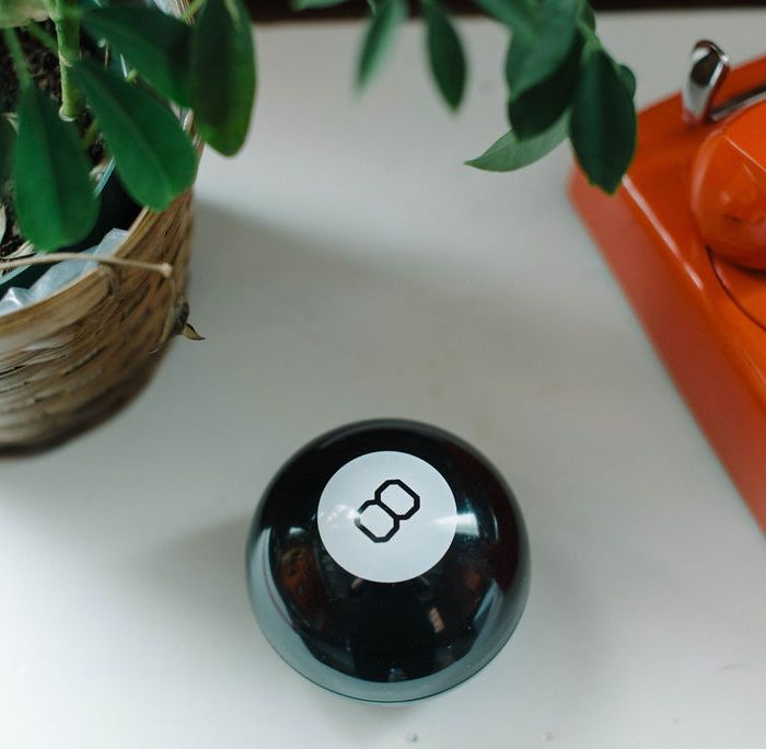 Magic 8 Ball on a white table next to a plant and orange telephone in the p7 office