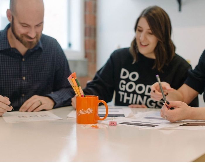 Three people sitting at a table collaborating in the project7 design office in des moines