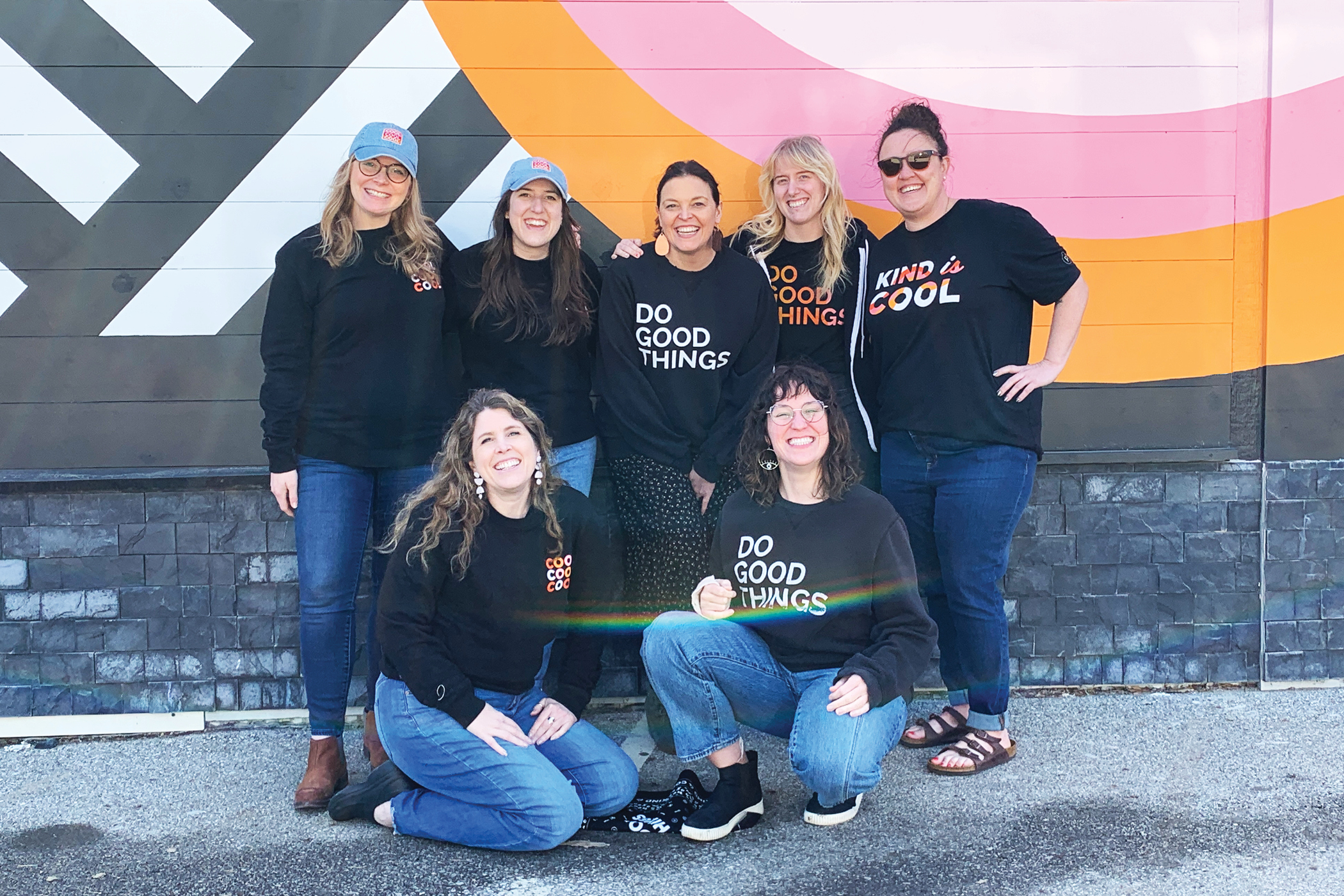 p7 team in project7 design merch in front of Cool to be kind mural in des moines