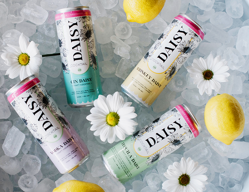 Daisy Cocktail Co. beverages sitting on ice with daisys and lemons
