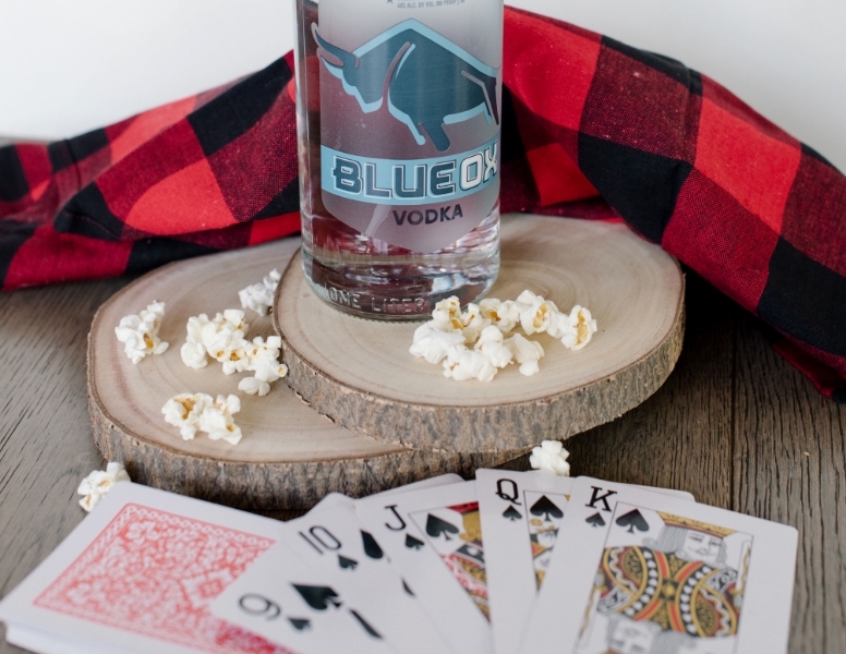 a bottle of Blue Ox vodka with playing cards and popcorn