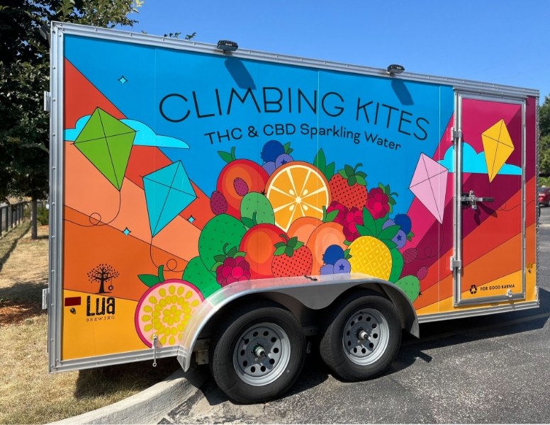 Climbing Kites branded trailer with a rainbow graphic, kites and illustrated fruits