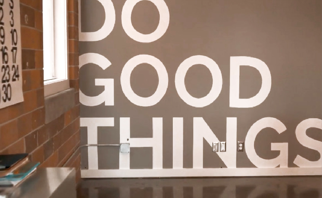 A gray wall with white letters reading "DO GOOD THINGS"