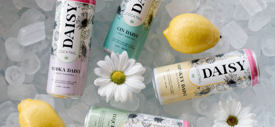 Four tall cans that say Daisy in a bucket of ice with daisy flowers and lemons.