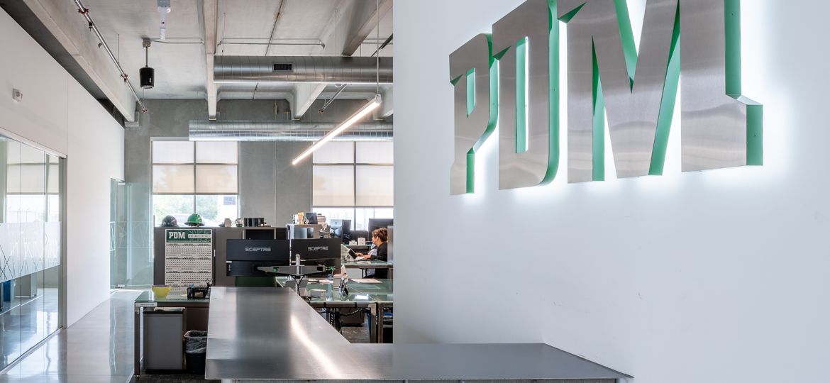 PDM corporate office entryway with custom concrete desk and illuminated steel sign