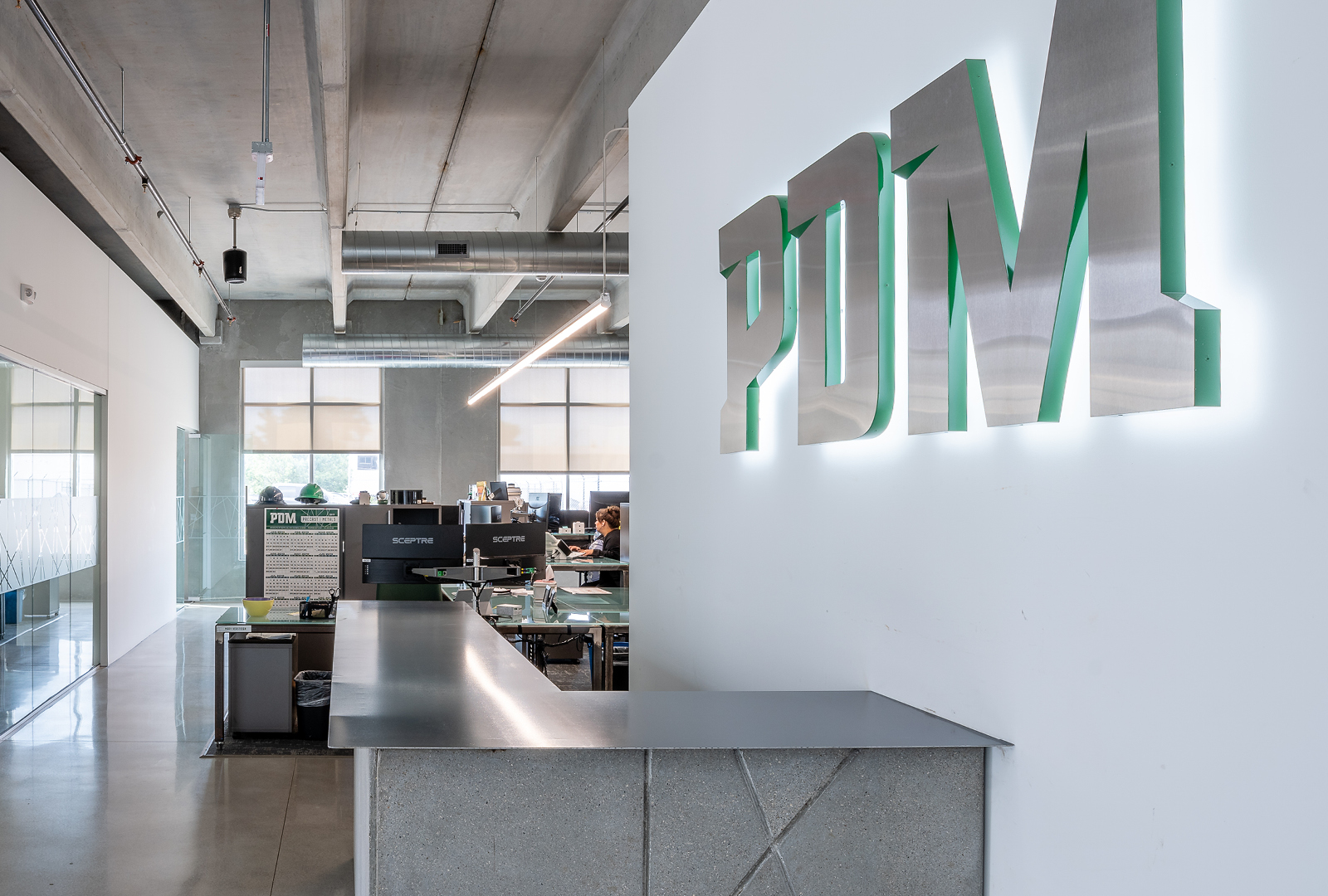 PDM corporate office entryway with custom concrete desk and illuminated steel sign