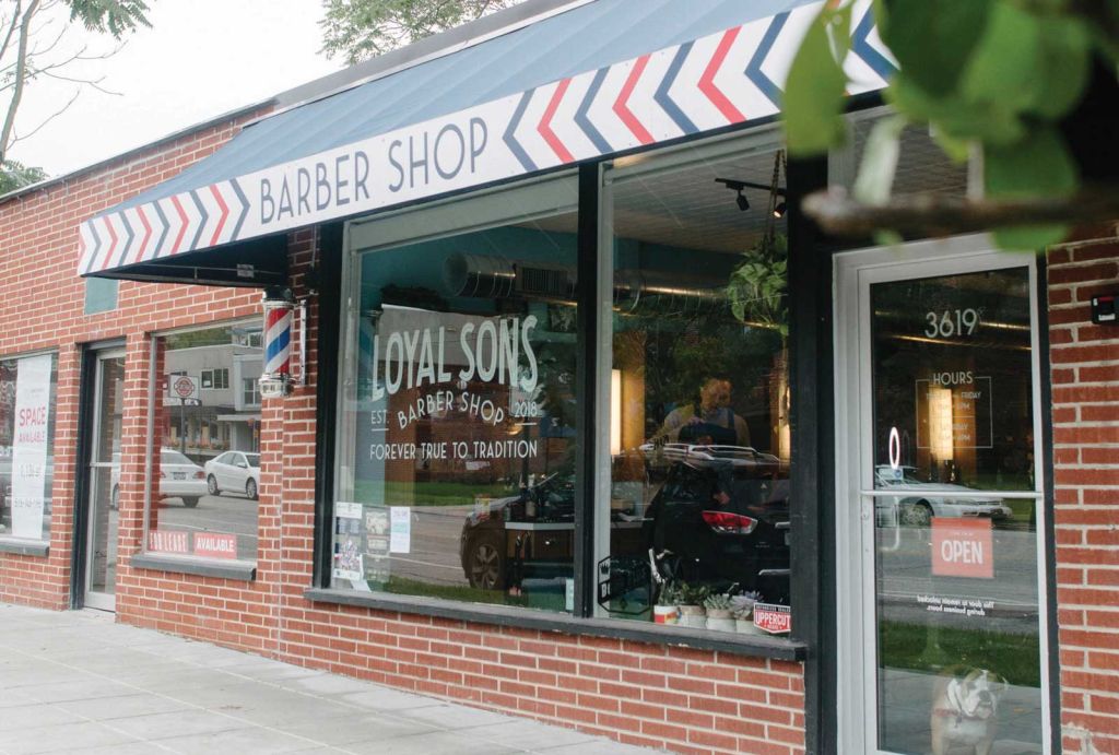 A brick building with an awning that is blue and red and says Barber Shop