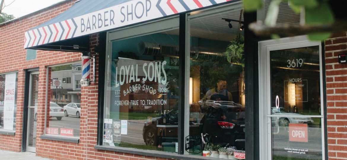 A brick building with an awning that is blue and red and says Barber Shop